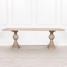 Load image into Gallery viewer, A beautifully handcrafted 240cm dining table made from solid mango wood, featuring a light rustic finish and two detailed hand-carved columned pedestal legs.