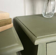 Load image into Gallery viewer, Two green side tables with a vase and books on top against a white wall.