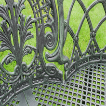 Load image into Gallery viewer, Close-up of a decorative metal bench with intricate patterns on a green background