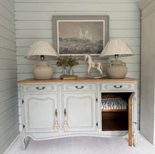 Load image into Gallery viewer, Vintage French Louis style sideboard painted in F&amp;B Lamp Room Grey with 2 stone lamps and decor on top against a light blue wall.