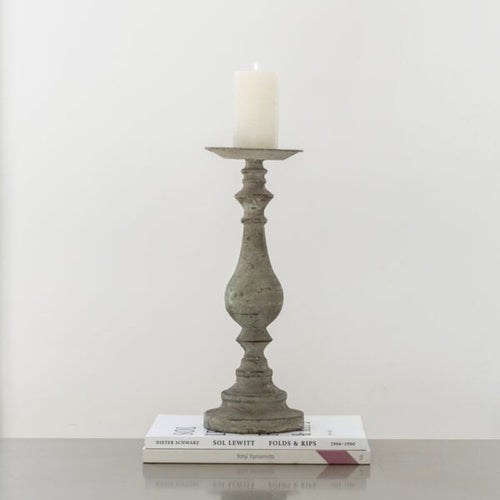 Decorative candlestick with a candle on top of two books against a plain background