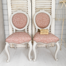 Load image into Gallery viewer, Pair of vintage chairs with pink upholstery and greige wooden frames against a white wall.