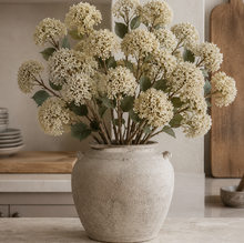 Load image into Gallery viewer, Decorative plant in a textured vase on a wooden surface with kitchen items in the background.